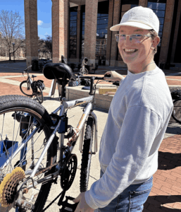 A volunteer smiling at the camera as he adjusts a bike on a repair stand.